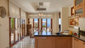 A spacious kitchen with a large island, wooden cabinets, and a view to the outdoors. - Elegant Villa Retreat with Infinity Pool & Scenic Views (Paphos)