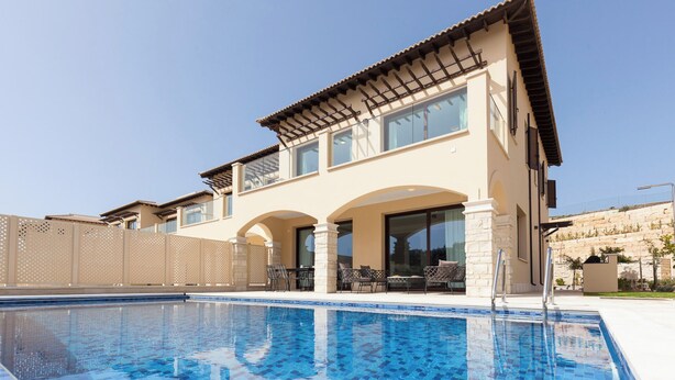 A two-story house with a swimming pool in front.