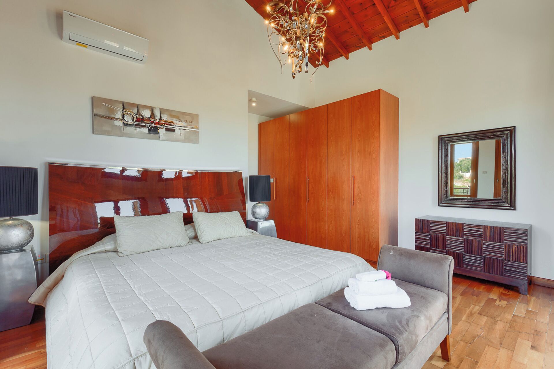 Ein Schlafzimmer mit einem großen Bett, einem Holzschrank und einem Spiegel.