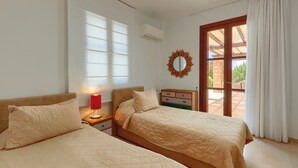 Une chambre avec deux lits, une lampe rouge, un miroir et une vue sur une terrasse extérieure.