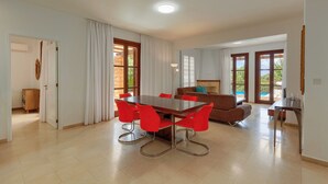 Un vaste espace de vie comprenant une table à manger et des chaises, un canapé et une vue sur une piscine, grâce à de grandes fenêtres.