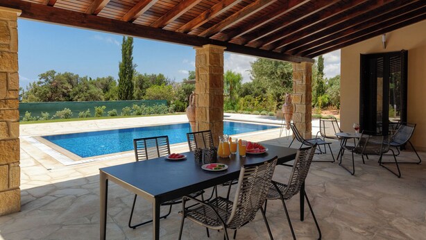 Un espace extérieur abrité comprenant une piscine, des piliers en pierre et du mobilier d’extérieur.