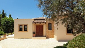 Une maison moderne à deux étages, avec un toit recouvert de tuiles, une porte en bois et un petit jardin.
