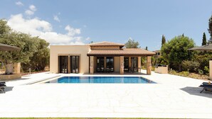 Une maison moderne dotée d’une piscine, de mobilier de jardin et d’un jardin.