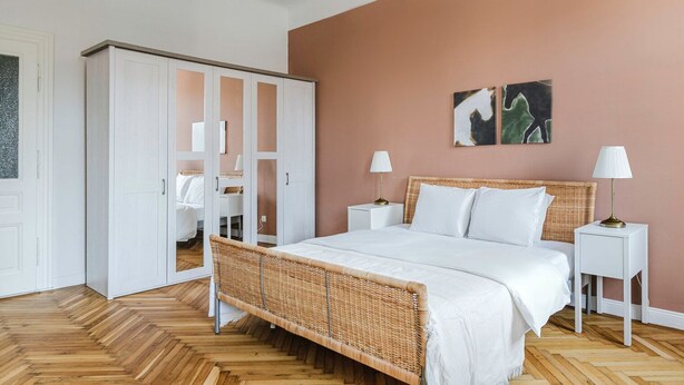 Een slaapkamer met een bed, nachtkastjes, een kledingkast en een hanglamp.