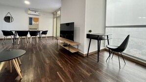 A modern office space with a large window, a flat-screen TV, and a wooden floor.