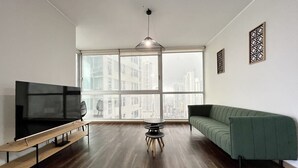 A modern living room with a large TV, a green sofa, and a wooden coffee table.