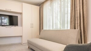 Ein modernes Wohnzimmer mit einem beigefarbenen Sofa, einem grauen Sessel und einem an einem weißen Schrank montierten Fernseher.