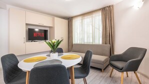 Ein modernes Wohnzimmer mit Essbereich, einer Couch und einem Fernseher, der 'NETFLIX' anzeigt.