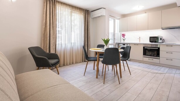 Eine moderne Küche mit Essbereich, inklusive Tisch und Stühlen, Backofen, Mikrowelle und Spüle.