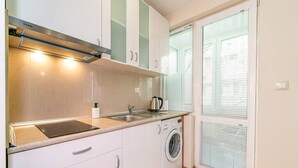 A compact kitchen with a built-in washing machine, a stove, and a sink. - Varna Central Studio (Varna)