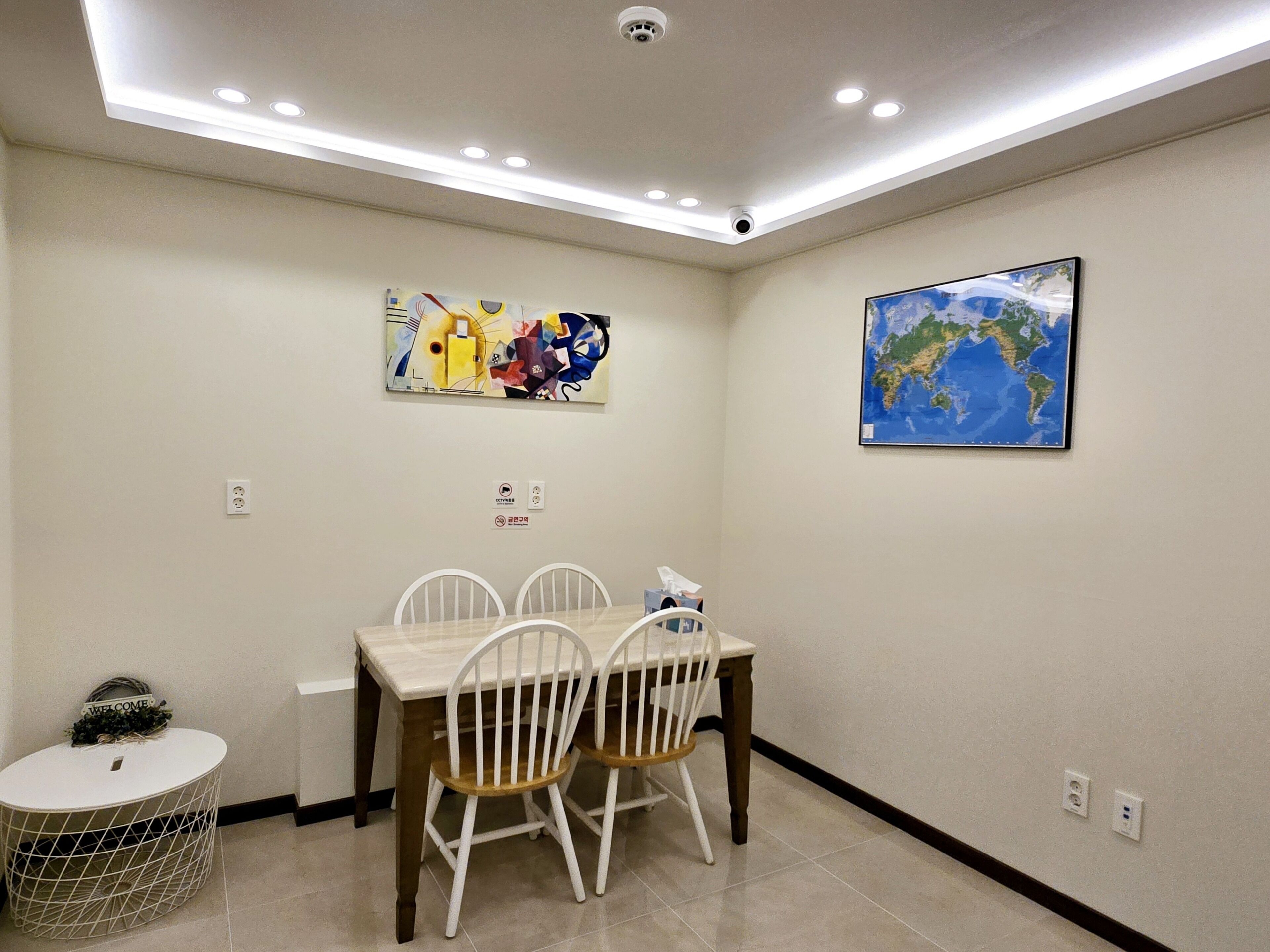 Un coin repas avec une table et des chaises, une carte accrochée au mur et un plafond doté d’un éclairage encastré.