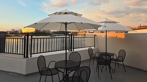 A rooftop terrace with outdoor seating and umbrellas, overlooking a cityscape. - Incheon Airport Guesthouse L (Incheon)