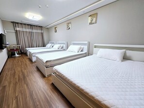 A hotel room with three single beds, a wooden floor, a flat-screen TV, and a small table with a chair. - Incheon Airport Guesthouse L (Incheon)