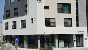 A modern building with a 'Guest House' sign, large windows, and a blue pedestrian sign. - Incheon Airport Guesthouse L (Incheon)