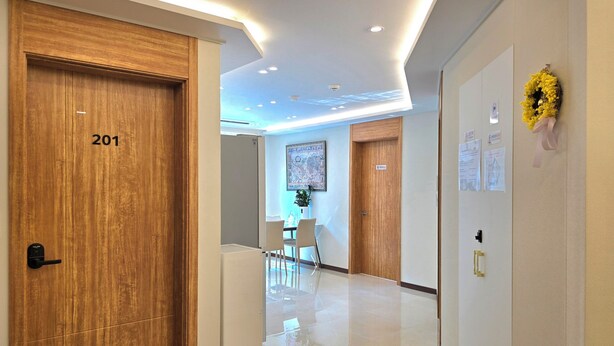A hotel corridor with wooden doors, a polished floor, and a dining area in the background. - Incheon Airport Guesthouse L (Incheon)