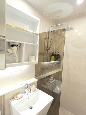 A modern bathroom with a glass-enclosed shower, a white sink, and a mirror with gold trim. - Incheon Airport Guesthouse L (Incheon)