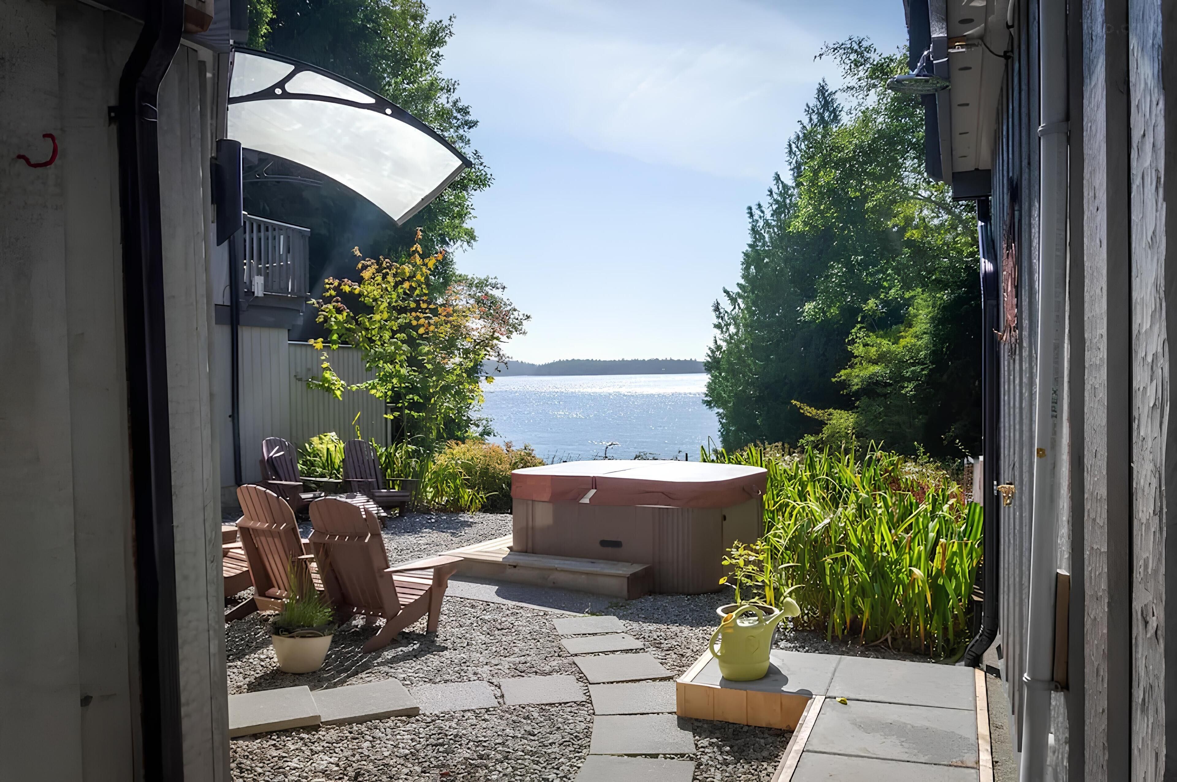 A patio with outdoor seating, a hot tub, and a view of a lake.