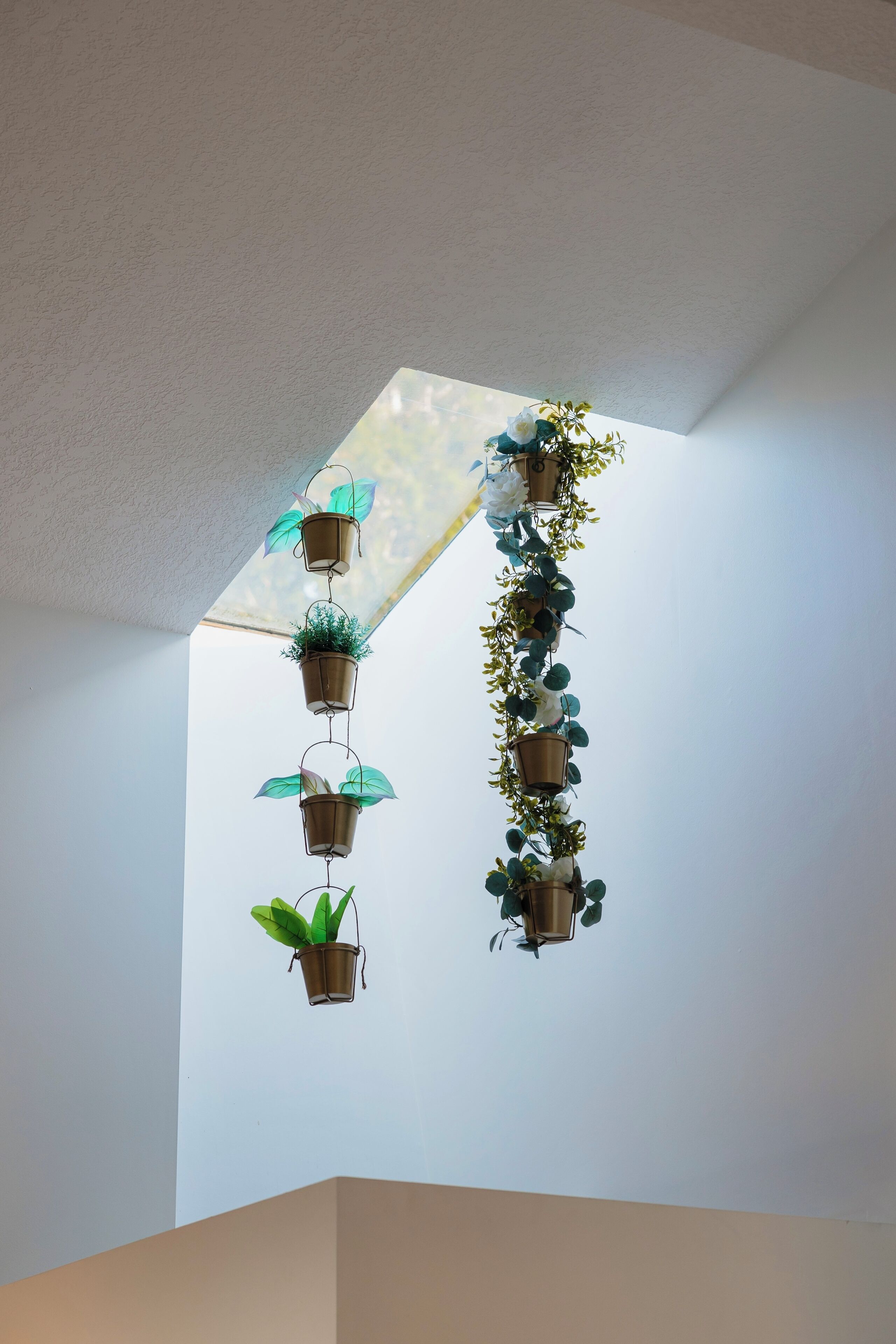 A ceiling with multiple hanging planters arranged in a vertical line.