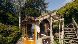 A wooden cabin with a glass enclosure, a door with a decorative handle, and a wooden staircase leading up to it. - Maison Tofino - Private Oceanfront (Tofino)