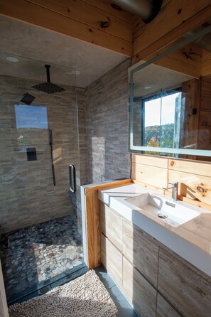 Un baño moderno con ducha de vidrio, muebles de madera y un espejo grande.