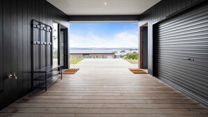A modern building with a wooden deck leading to a large open door. - The Outlook on Mount Louis - 2 Bedroom (Tinderbox)