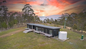A modern house with a flat roof, large windows, and a deck. - The Outlook on Mount Louis - 1 Bedroom (Blackmans Bay)