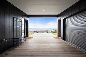 A modern building with a wooden deck leading to a large open door. - The Outlook on Mount Louis - 1 Bedroom (Blackmans Bay)