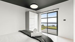 A modern bedroom with a large bed, a wardrobe, and a sliding glass door leading to a balcony with a view of the outdoors. - The Outlook on Mount Louis - 1 Bedroom (Blackmans Bay)