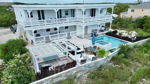 Une maison à deux étages dotée d’un balcon, d’une piscine et d’un espace salon extérieur.