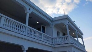 Un bâtiment doté d’un balcon et un ciel dégagé parsemé de nuages.