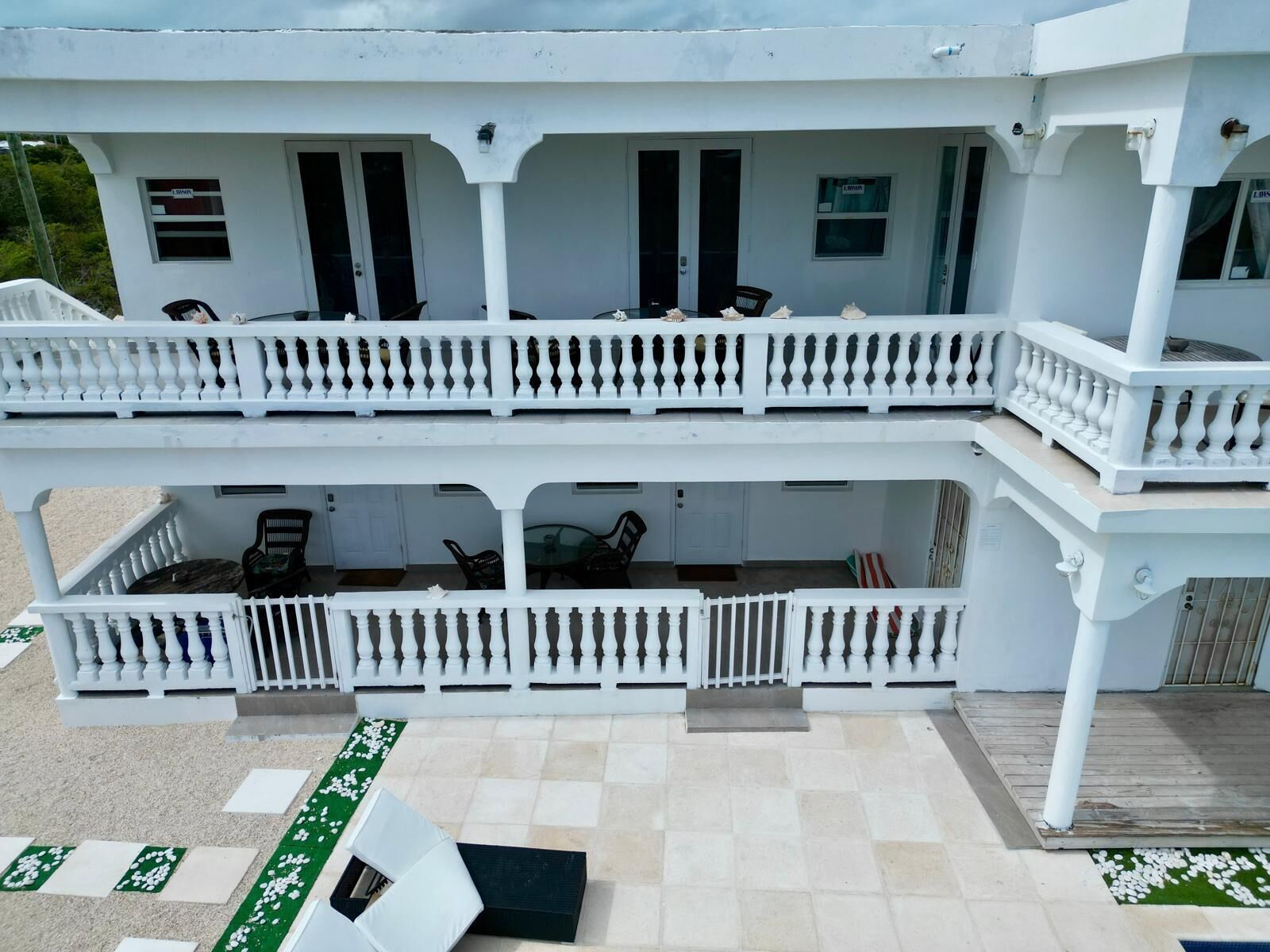A two-story building with a white exterior, balconies, and a covered outdoor seating area.