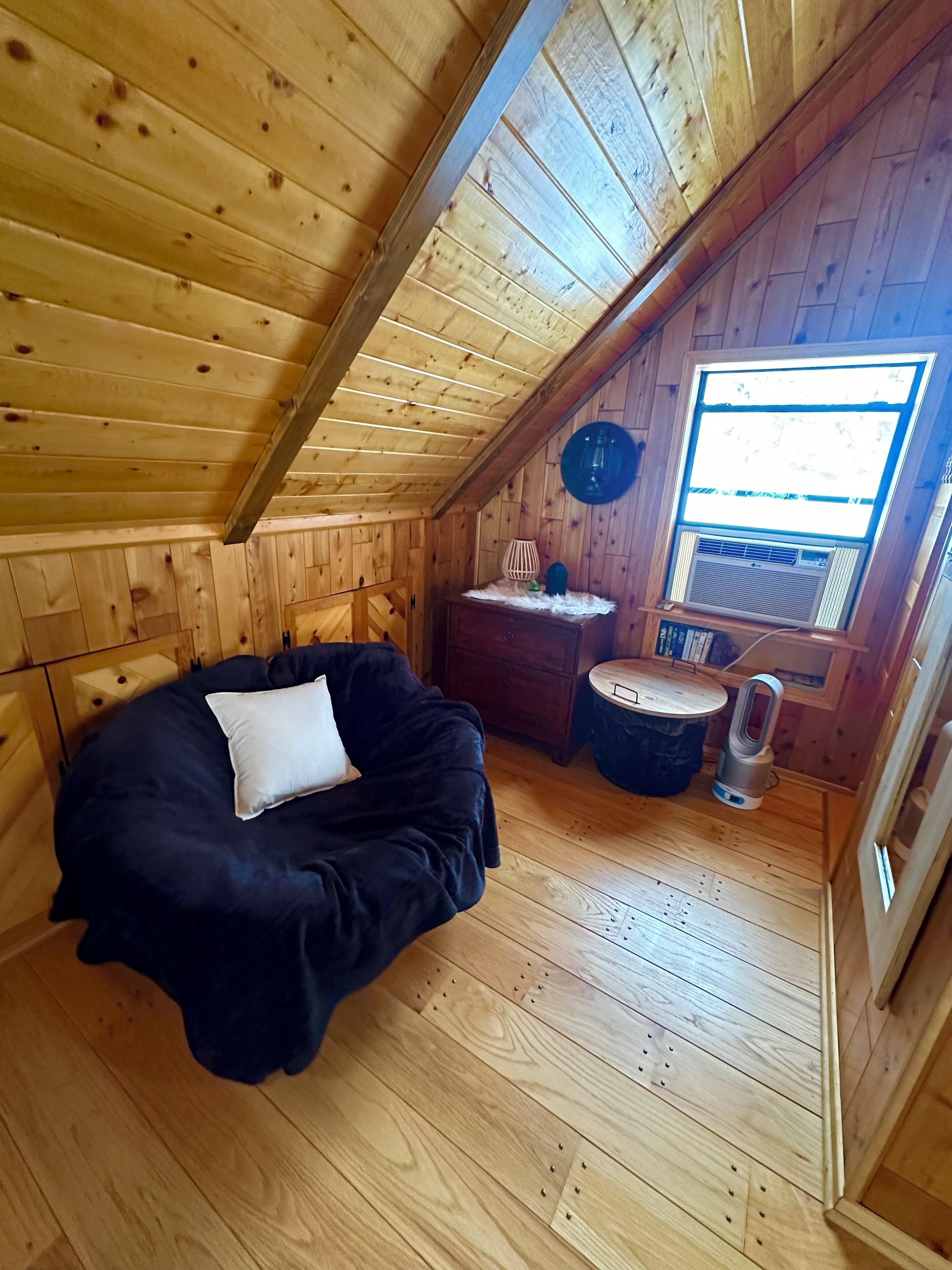 Ein gemütliches Dachzimmer mit Bett, kleinem Tisch und Fenster.