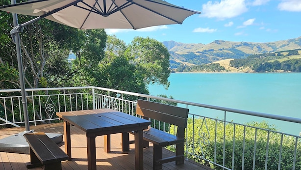 Une terrasse en bois avec une table et des bancs, donnant sur un lac dont l’arrière-plan est constitué de collines.