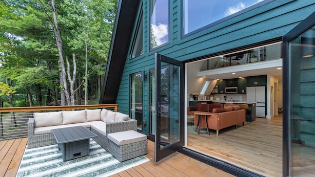Ett modernt hus med en terrass, en soffa och en matplats.