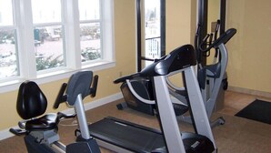 Une salle de sport équipée de tapis de course et d’appareils elliptiques, dotée de grandes fenêtres et offrant une vue sur l’extérieur.