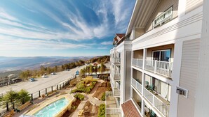 Un hôtel à plusieurs étages doté de balcons, d’une piscine et offrant une vue sur une route et des montagnes.