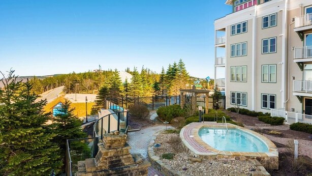 Un hôtel à plusieurs étages doté d’une piscine, entouré d’arbres et offrant une vue sur un ciel dégagé.