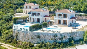 Una villa a più piani con piscina e area salotto esterna.