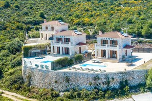 A multi-story villa with a swimming pool and outdoor seating.