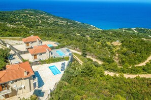A hillside property with multiple buildings, outdoor swimming pools, and a view of the sea. - Sunset Vista Villas Deluxe III (Zakynthos)