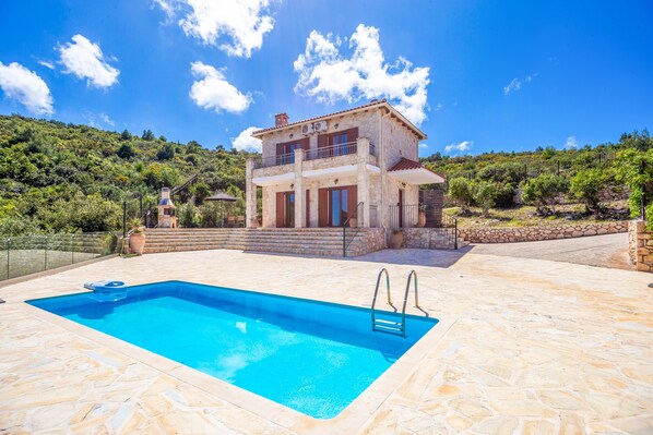 A two-story stone house with a swimming pool, surrounded by a stone patio and lush greenery. - Sunset Vista Villas Deluxe III (Zakynthos)