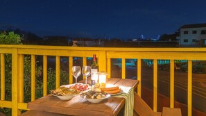 Une table dressée avec de la nourriture et des boissons sur un balcon, avec vue sur le ciel nocturne.