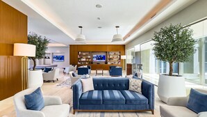 A modern living room with a blue sofa, white armchairs, and a large TV in the background. - Burj Khalifa Pool View Dubai Mall Address Opera 2B (Dubai)