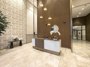 A reception desk with a marble top, a wooden panel wall, and hanging pendant lights.