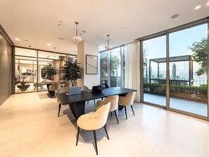 A modern dining area with a large table and chairs, large windows with a view of the outdoors, and a kitchen area visible through glass doors. - Downtown 1B Burj Khalifa Infinity Pool Dubai Mall (Dubai)