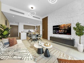 A modern living room with a sofa, coffee table, and a flat-screen TV mounted on a textured wall.