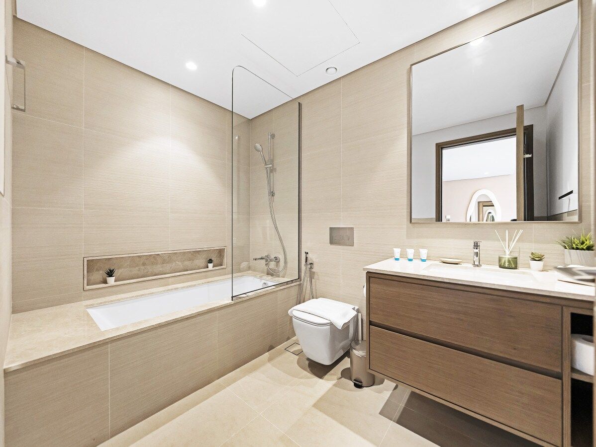A modern bathroom with a bathtub, toilet, and vanity.