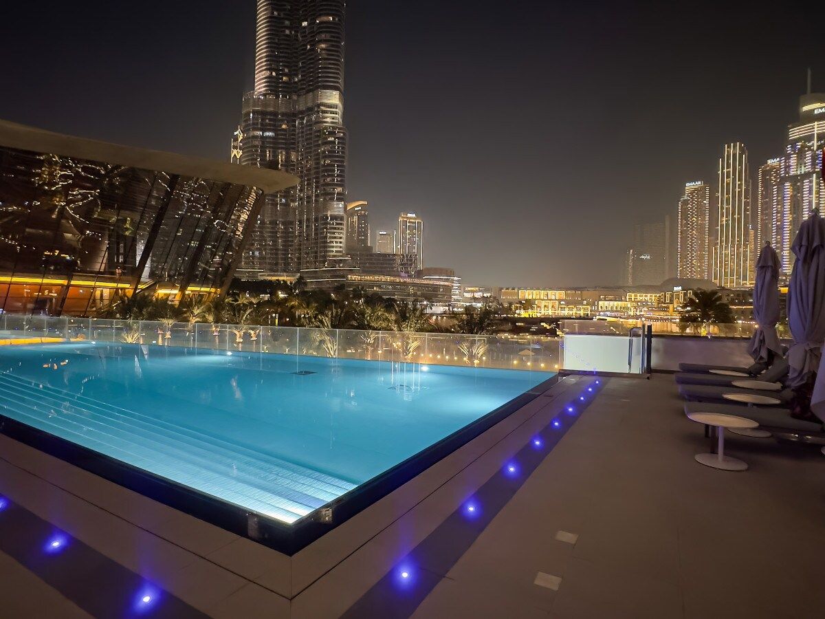 Una piscina en la azotea con vistas a un horizonte urbano nocturno.