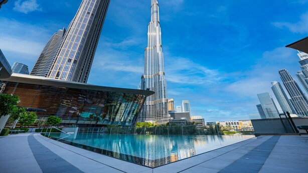 A modern building with a reflective pool in front, surrounded by other high-rise buildings. - New 1BR |Burj Khalifa Infinity Pool |Dubai Mall (Dubai)